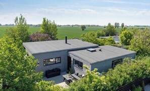 Ein modernes, zweistöckiges Haus mit Flachdach, großen Fenstern und einer Terrassenfläche.