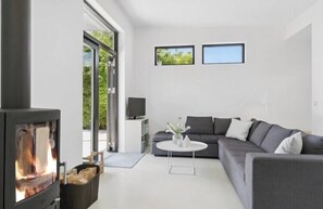 Ein modernes Wohnzimmer mit Kamin, grauem Sofa und Fernseher.