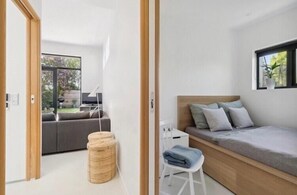 Ein modernes Schlafzimmer mit einem Bett, einem kleinen Tisch, einem Sessel und einem Fenster.