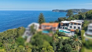 En fastighet vid kusten med en swimmingpool, modern arkitektur och utsikt över havet.
