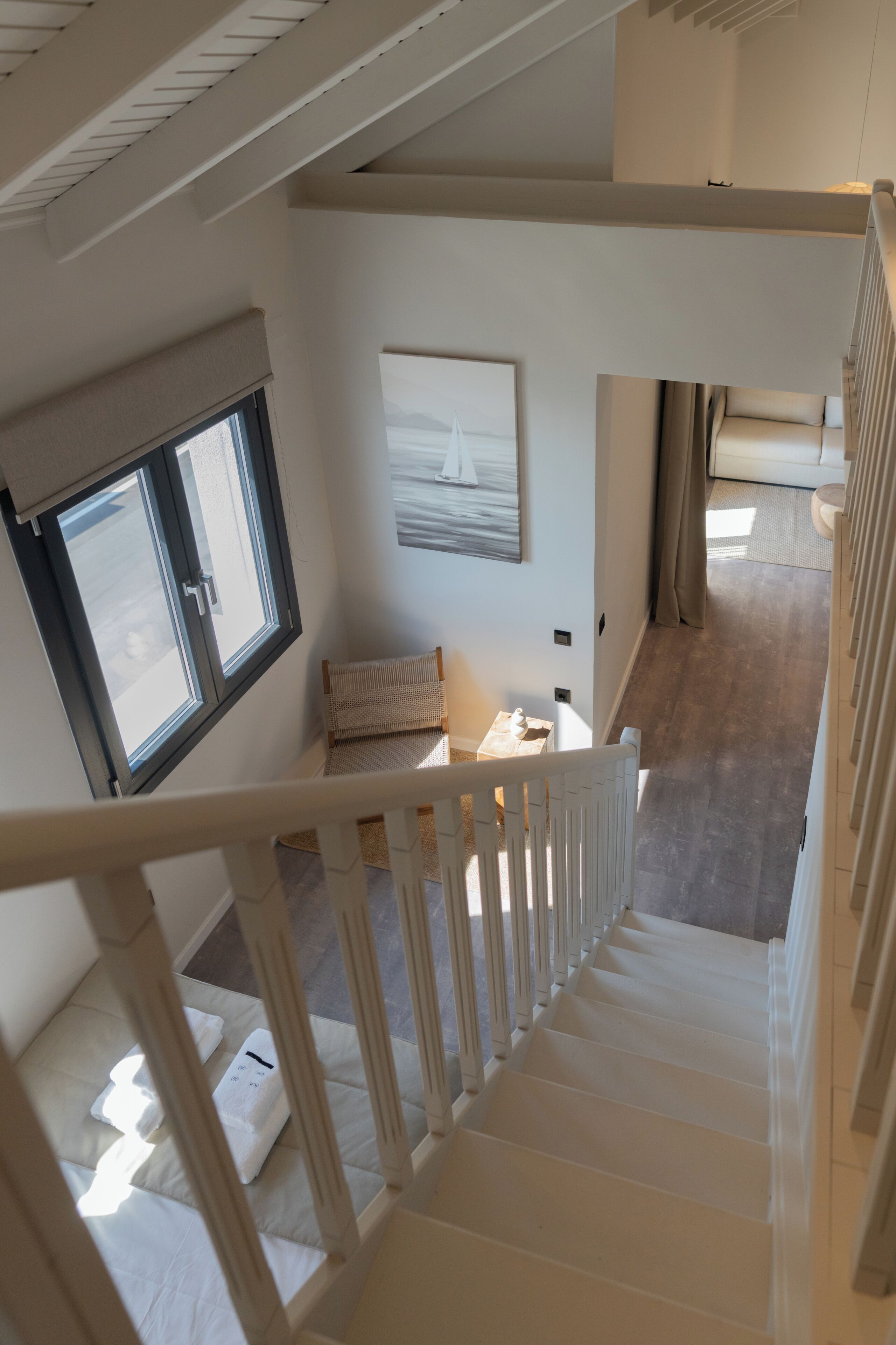 A staircase leading to a bedroom with a bed, a window, and a painting on the wall.