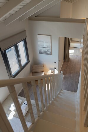 A staircase leading to a bedroom with a bed, a window, and a painting on the wall. - Ichos Apartments (Volissos)