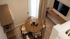 A modern living space with a dining area, a TV, and a staircase. - Ichos Apartments (Volissos)
