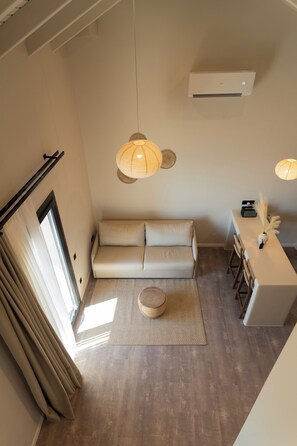 A modern living room with a sofa, a small round table, and a dining area with chairs.