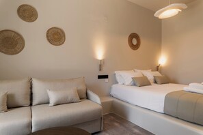 A modern bedroom with a sofa, a bed, and decorative wall hangings.