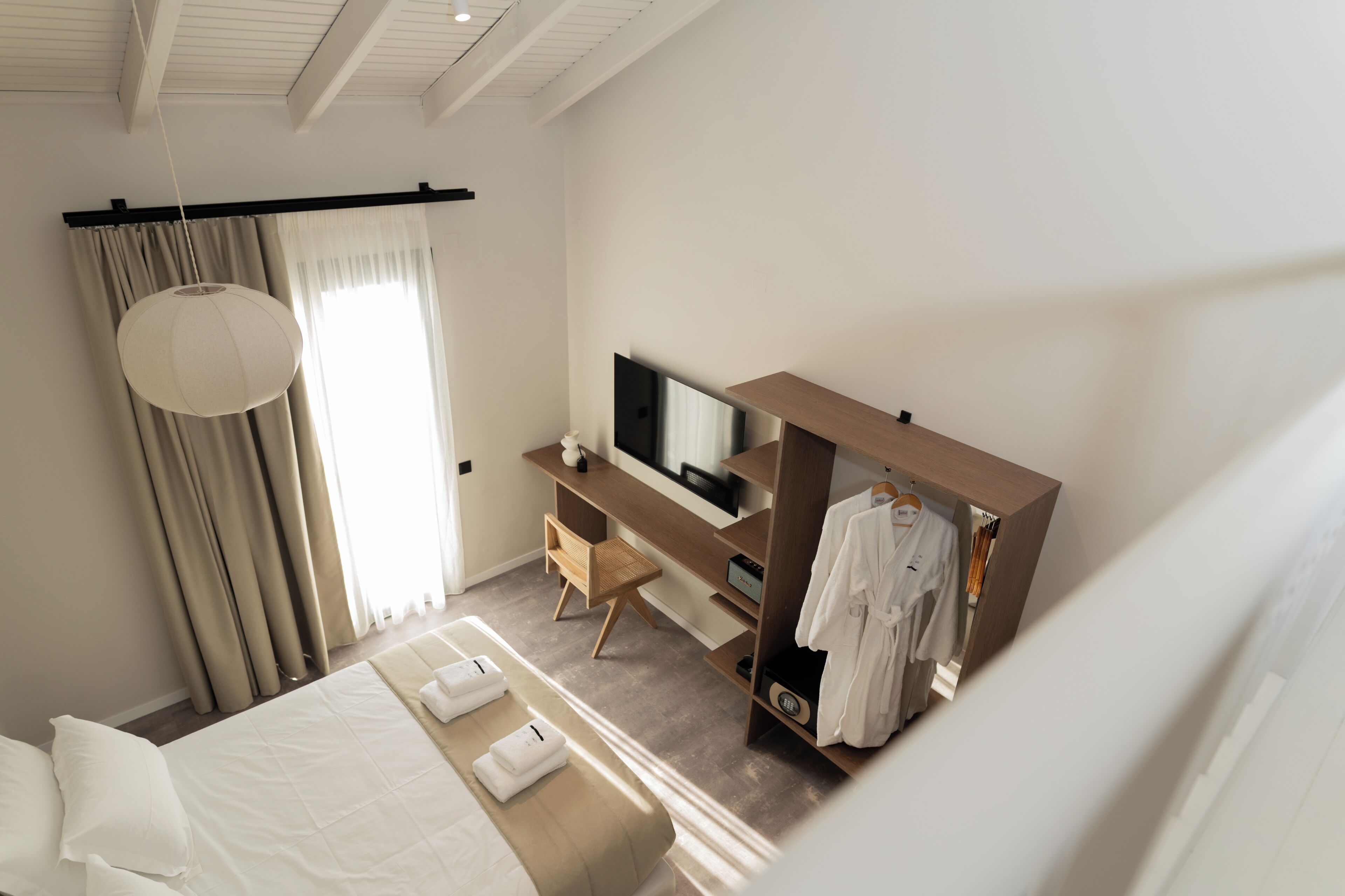 A modern bedroom with a bed, a desk, a TV, and a walk-in closet.