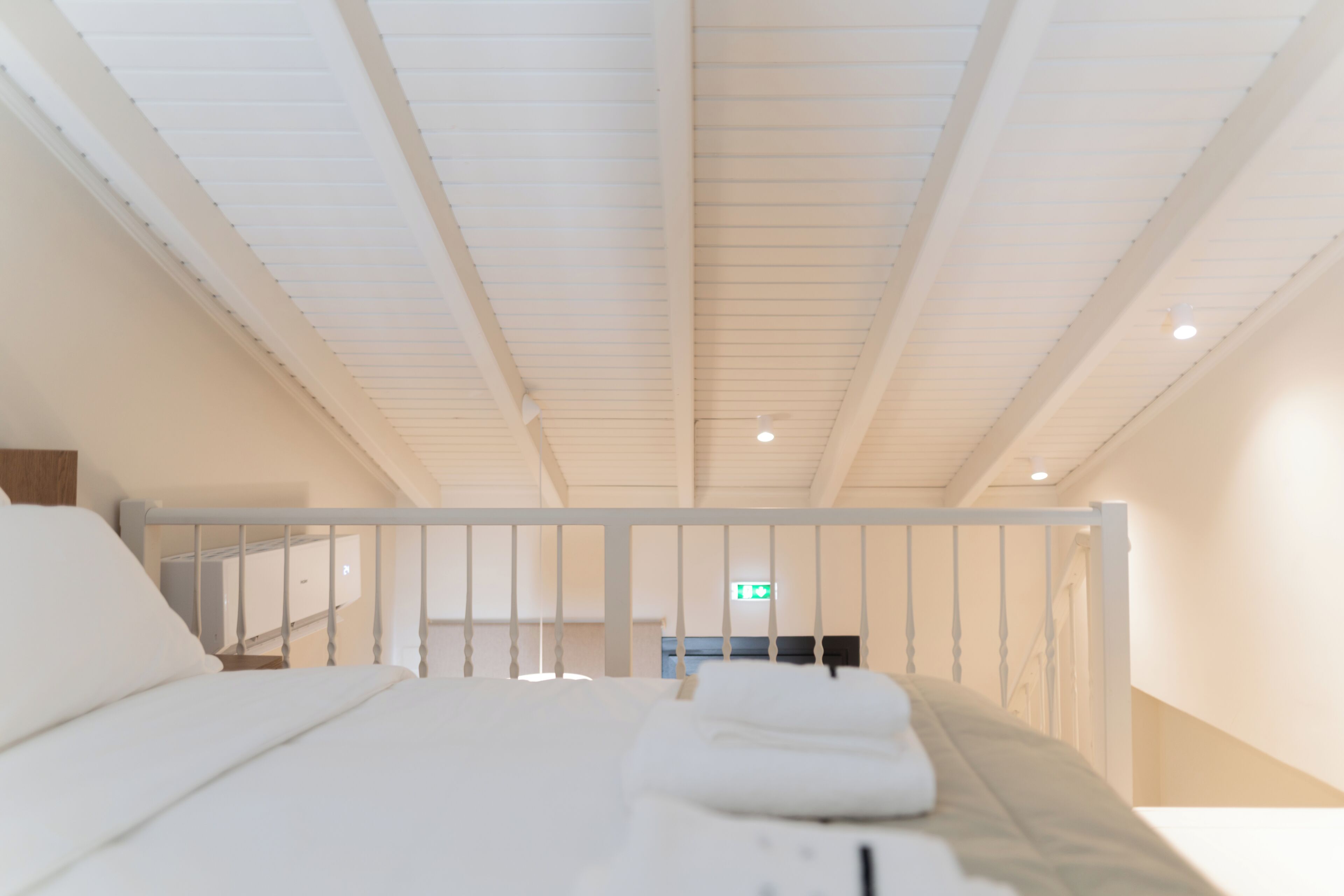 A hotel room with a bed, a nightstand, and a view of the hallway.