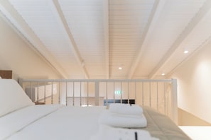 A hotel room with a bed, a nightstand, and a view of the hallway.
