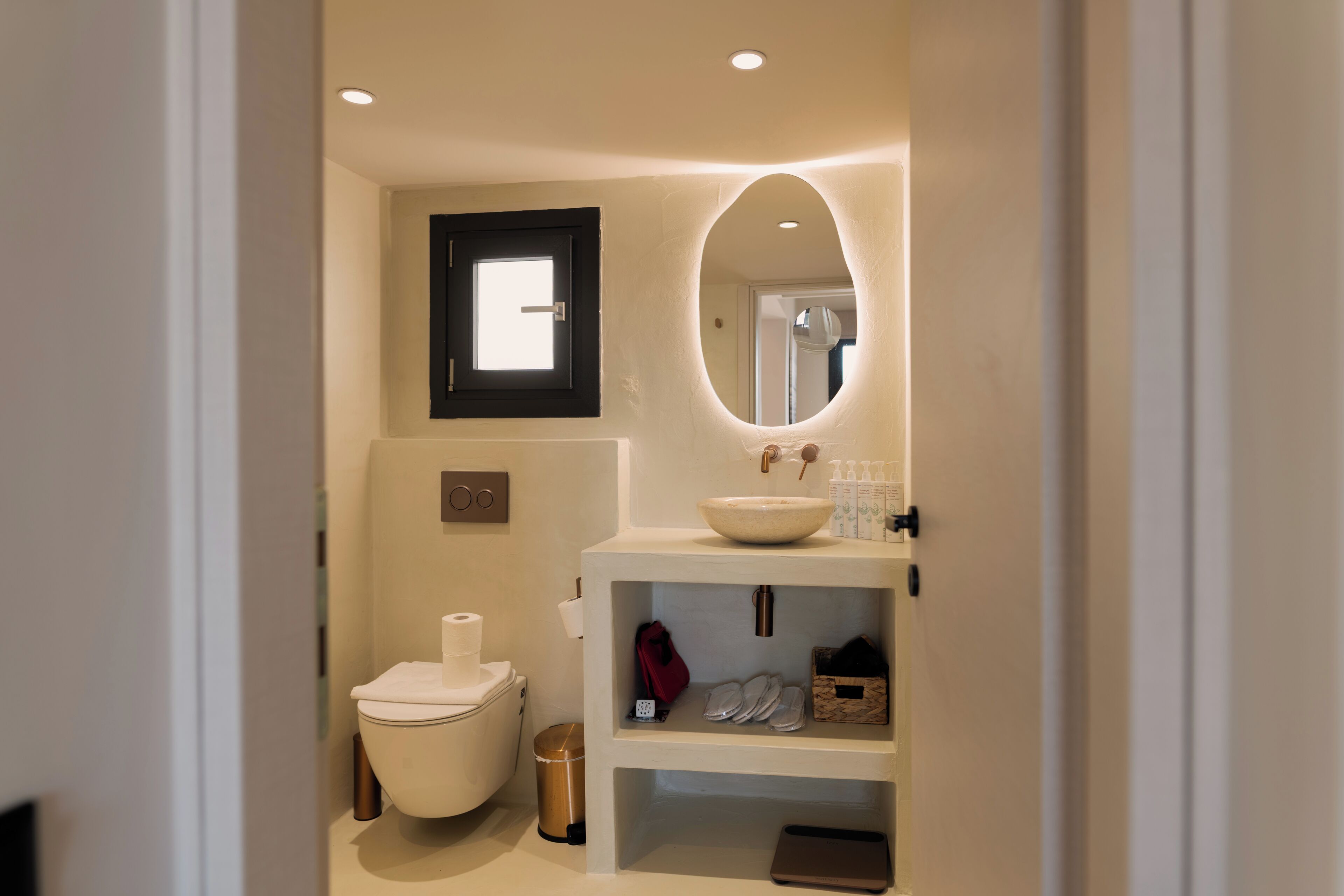 Un bagno compatto con il water, un lavabo con bacino a incasso e uno specchio.