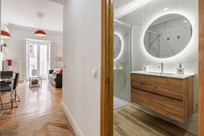 A modern bathroom with a marble vanity, a large mirror, and a glass shower enclosure. - Stylish Apartment in Downtown Madrid | 2 Min to Puerta del Sol (Madrid)