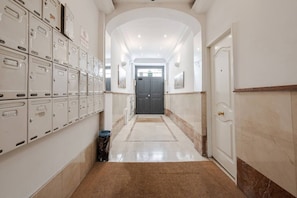 A hallway with lockers, a trash bin, and a door at the end. - Stylish Apartment in Downtown Madrid | 2 Min to Puerta del Sol (Madrid)