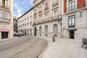 A street with buildings, a sidewalk, and a few parked cars. - Stylish Apartment in Downtown Madrid | 2 Min to Puerta del Sol (Madrid)