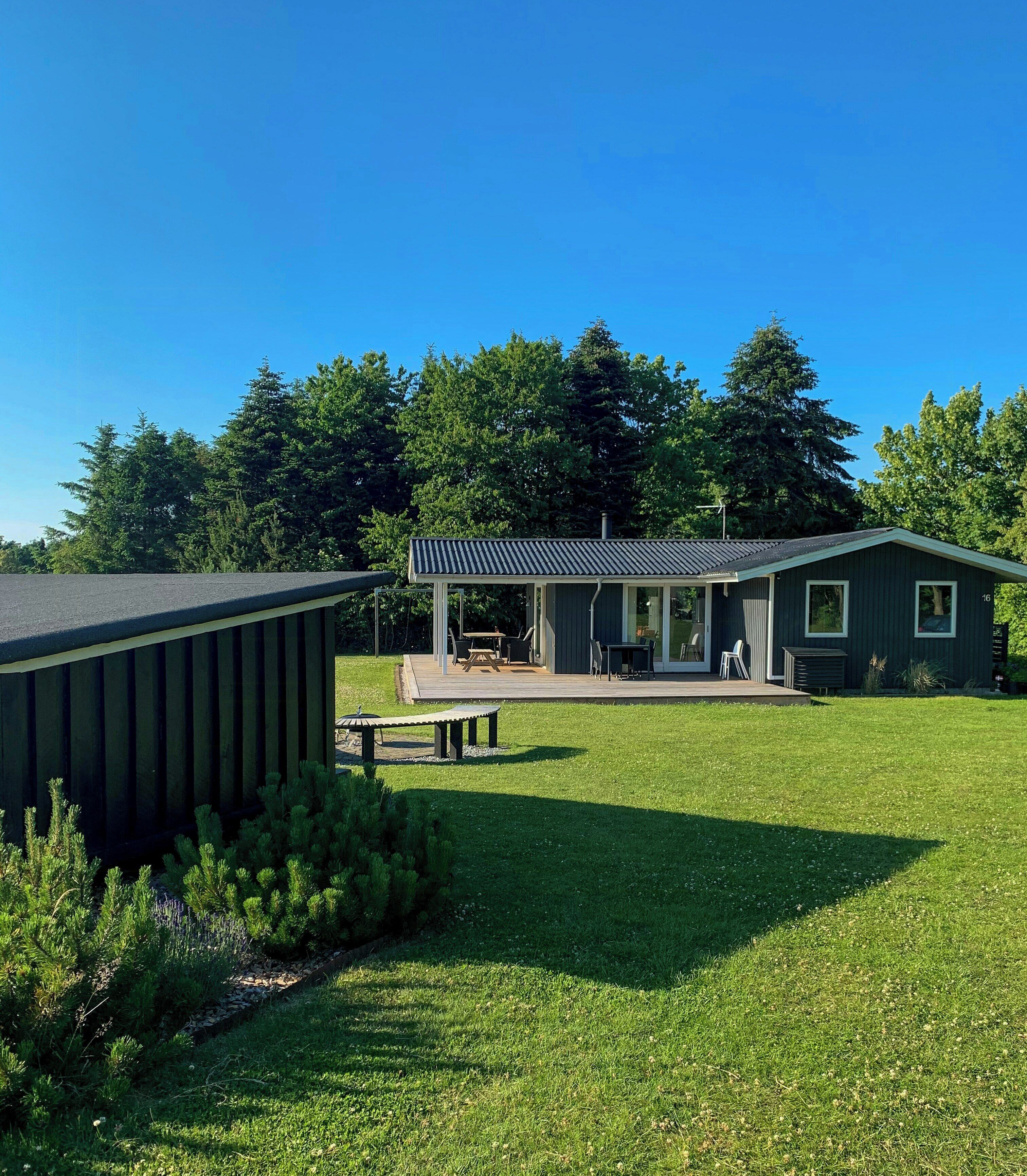 A modern building with a covered patio, outdoor seating, and a well-maintained lawn.