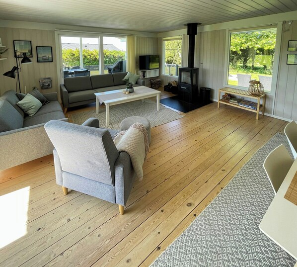 A spacious living room with a sofa, coffee table, and a fireplace. - Summer house near Bønnerup Beach (Glesborg)