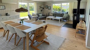 Un vaste espace de vie comprenant une table à manger, des canapés et une cheminée.