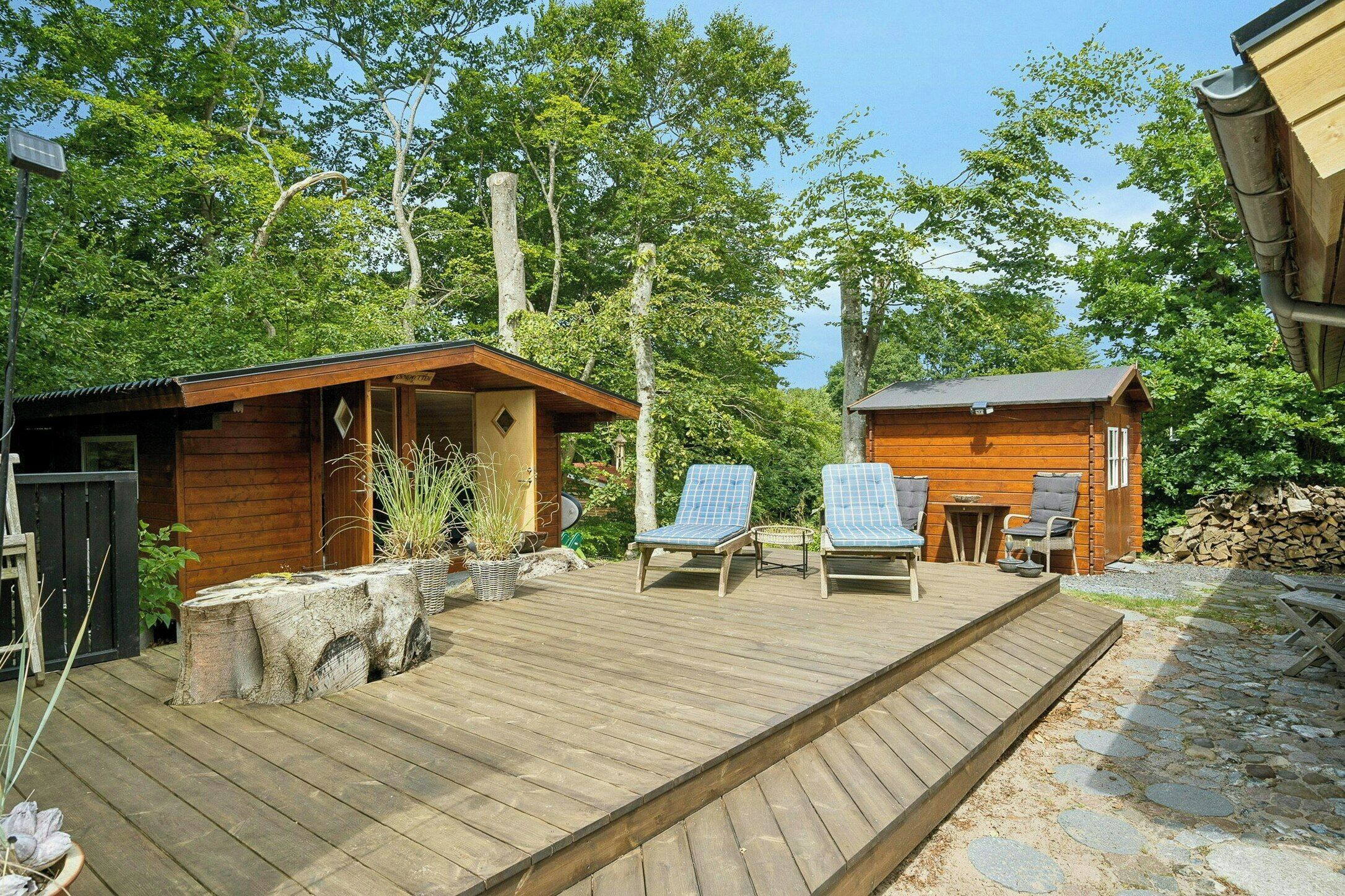 A wooden deck with lounge chairs, a small wooden building, and a stone pathway.