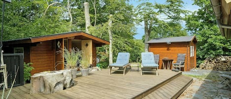 A wooden deck with lounge chairs, a small wooden building, and a stone pathway.
