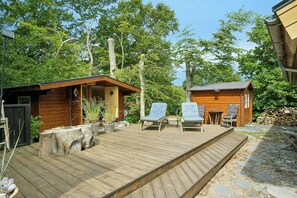 Eine Holzterrasse mit Liegestühlen, ein kleines Holzgebäude und ein Steinweg.