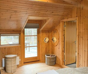 Ein Holzblockhaus-Innenraum mit großem Fenster, einer Tür und einem Korbwäschesammler.