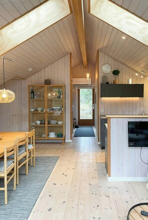 Eine moderne Küche mit Holzausstattung, ein Essbereich mit Tisch und Stühlen sowie ein Blick durch die Tür.