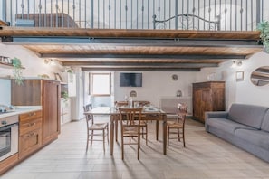 Un comedor con una mesa y sillas de madera, un sofá gris y una escalera que sube a un nivel superior.