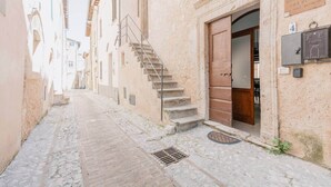 Une ruelle étroite pavée, bordée de bâtiments historiques, avec un escalier menant à une porte.