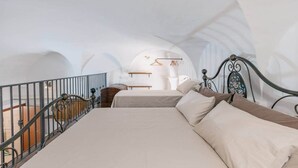 Une chambre à coucher avec un lit, un luminaire suspendu et une vue sur un balcon.