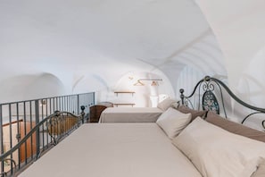 A bedroom with a bed, a hanging light fixture, and a view of a balcony.