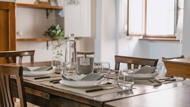 Une table à manger dressée avec des assiettes, des verres, des couverts et une bougie.