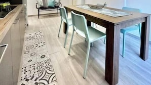 A modern kitchen with a dining area, a patterned rug, and a pendant light. - Hostdomus - Garden Suite (Finale Ligure)