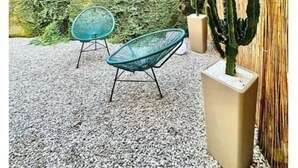 A patio area with a cactus, two chairs, and a textured wall. - Hostdomus - Garden Suite (Finale Ligure)