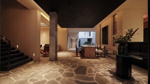 A spacious interior with a stone floor, a central island with seating, and a staircase on the left.