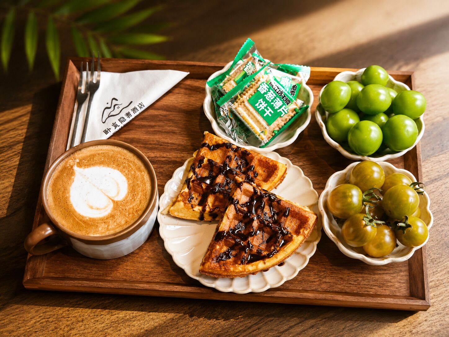 Una bandeja con una taza de café, una porción de tarta, un bol de tomates verdes y una bolsa de galletas.