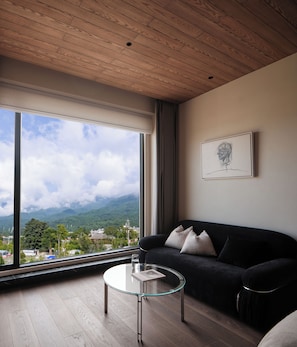 A modern living room with a large window, a black sofa, a glass coffee table, and a framed picture on the wall. - Dali Wolan Hidden Luxury Hotel (Dali)