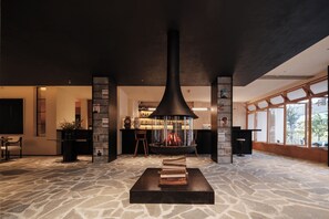 A modern interior with a central fireplace, stone flooring, and large windows. - Dali Wolan Hidden Luxury Hotel (Dali)