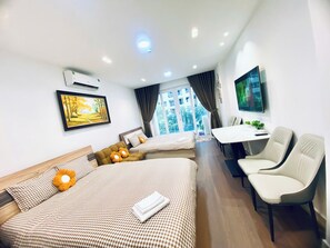 A hotel room with a bed, two sofas, a dining table, chairs, a TV, and a window with a view. - Apartment near Tan Son Nhat Airport (Tan Son Hoa)