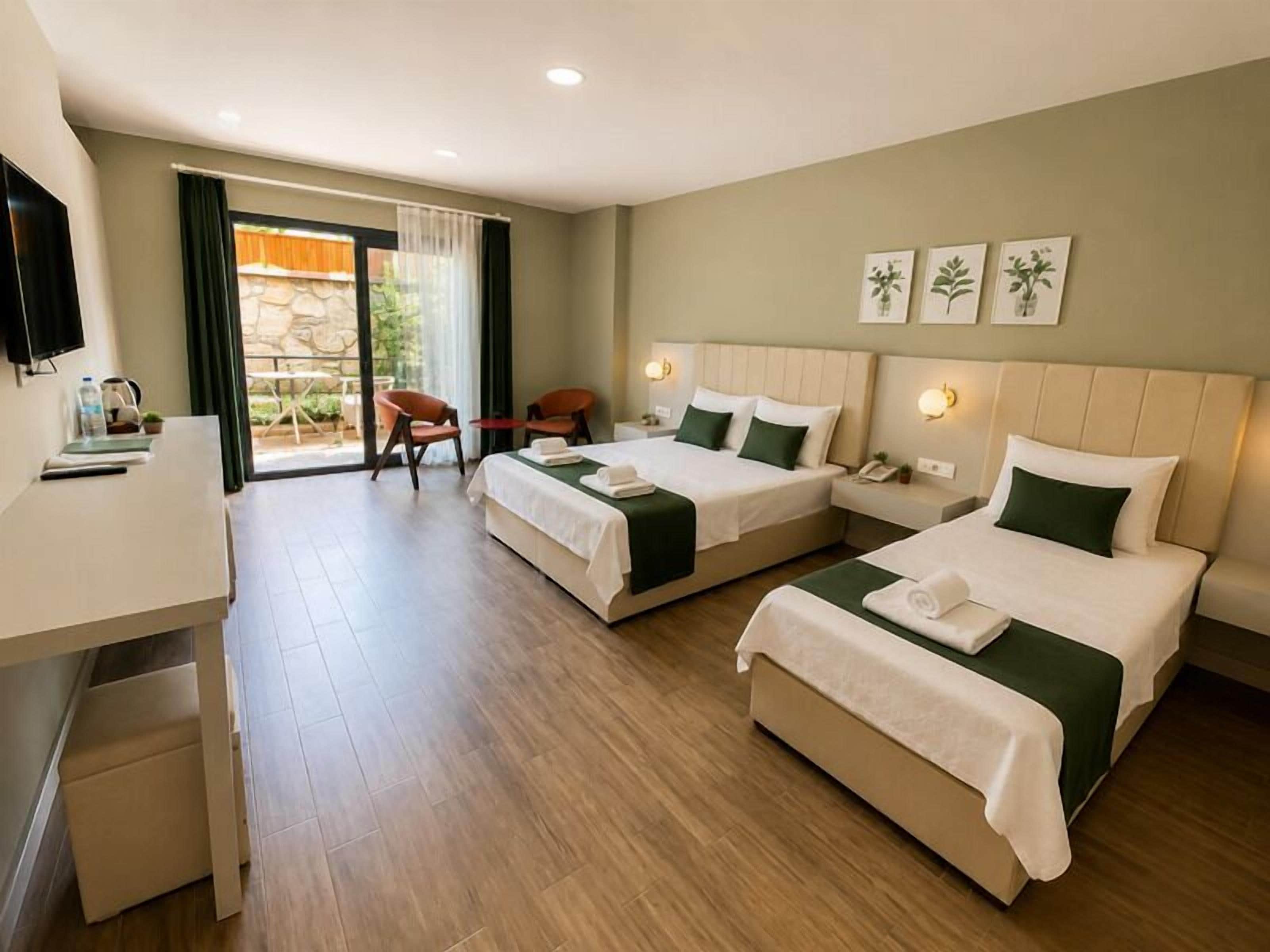 A hotel room with two beds, a desk, a chair, and a TV.