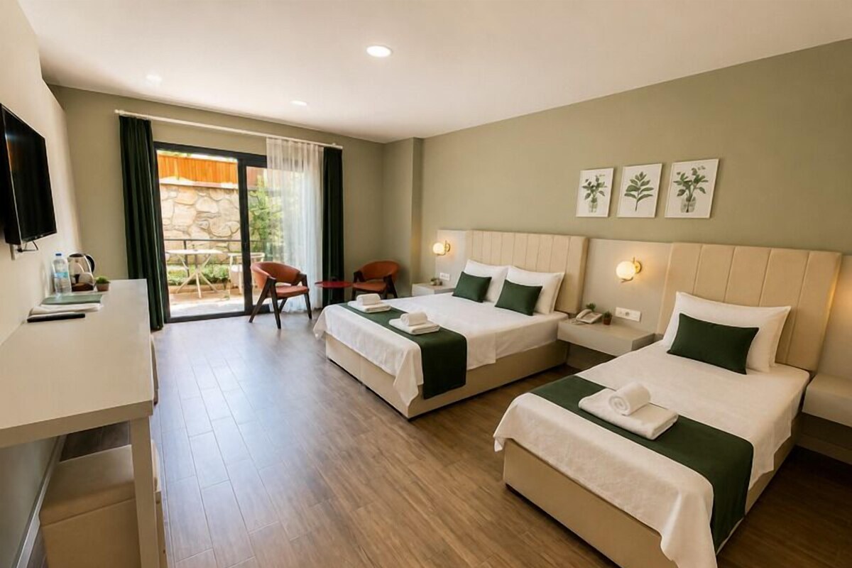 A hotel room with two beds, a desk, a chair, and a TV.