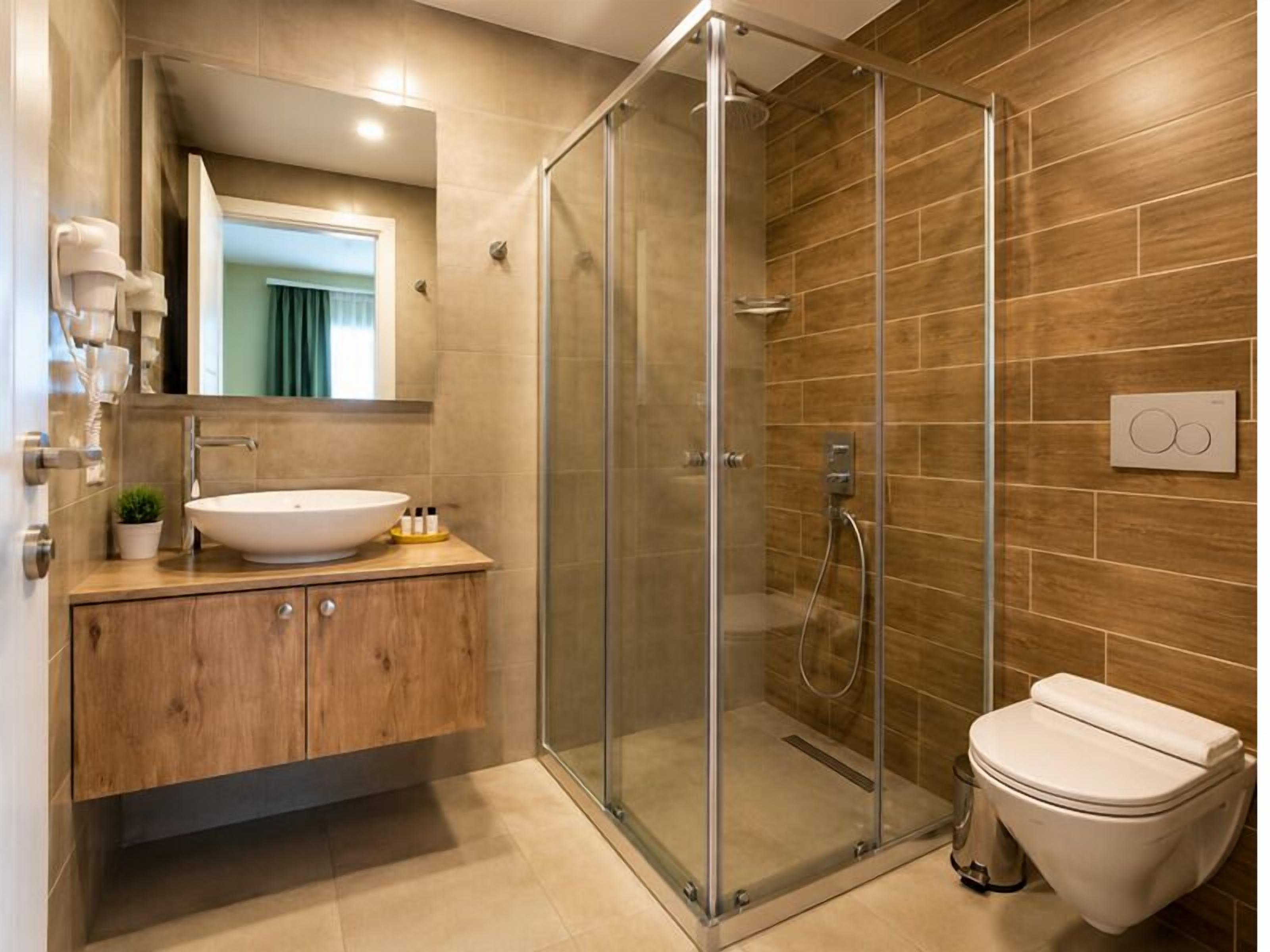 A modern bathroom with a glass-enclosed shower, a white sink, and a wooden vanity.