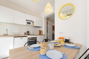 Eine moderne Küche mit weißen Schränken, einer Mikrowelle und einem Essbereich mit einem Holztisch für zwei Personen.