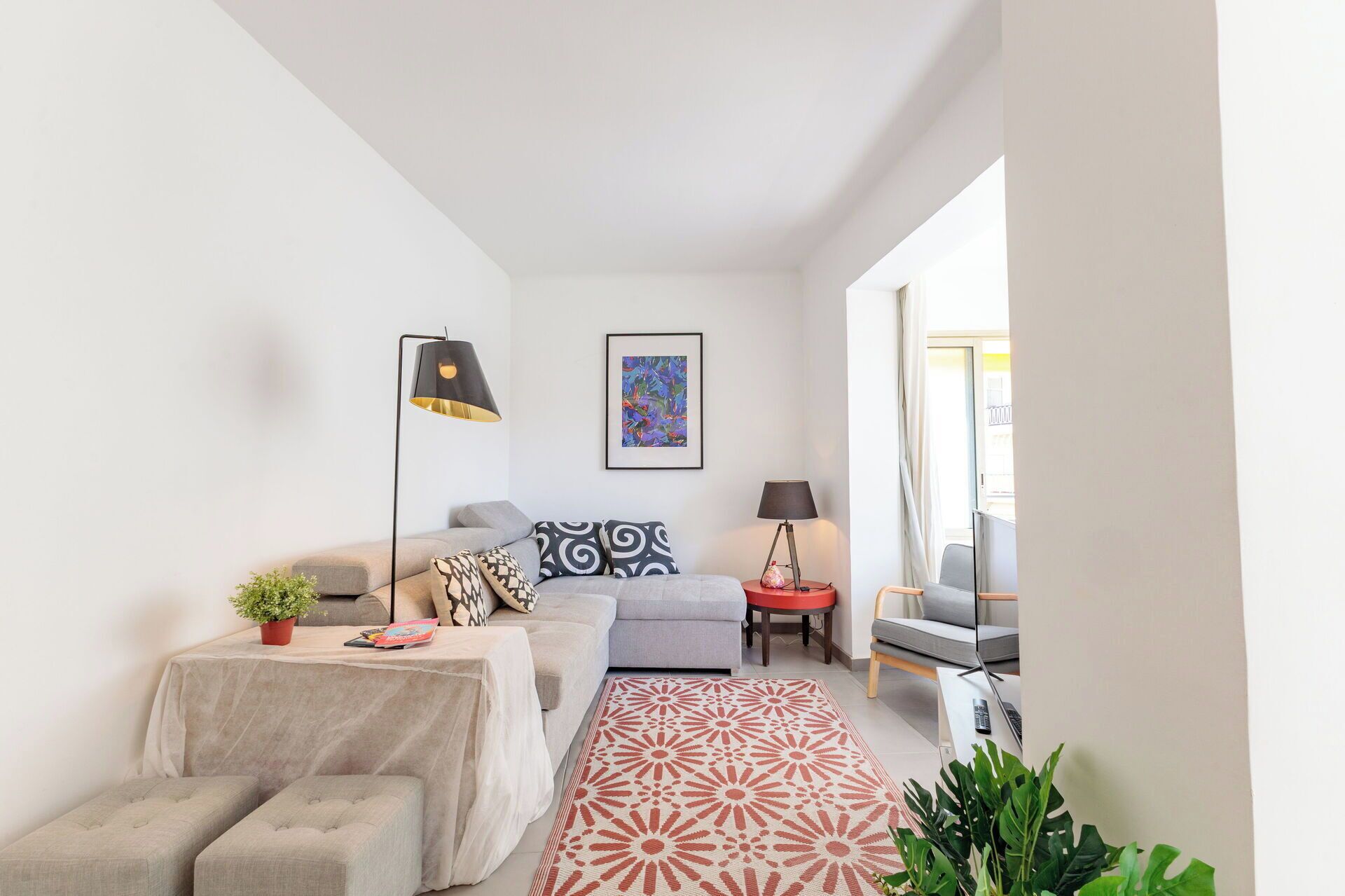 Uma sala de estar moderna com sofá, mesa de centro, abajur e tapete estampado.