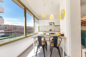 Eine moderne Küche mit großem Fenster, ein Essbereich mit Stühlen und Blick auf einen Tennisplatz.