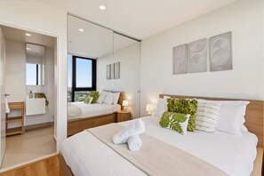 Ein modernes Hotelzimmer mit einem großen Bett, einem Spiegel, einem Badezimmer und Blick auf die Stadt.