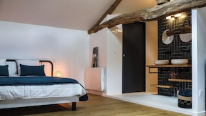 Ein Schlafzimmer mit Bett, einem Holzbalken an der Decke, einer Wand mit schwarzen Fliesen und einer weißen Tür.