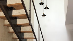 Eine Treppe mit Holzbodenstufen und Metallgeländern, eine hängende Leuchte und ein Blumentopf.