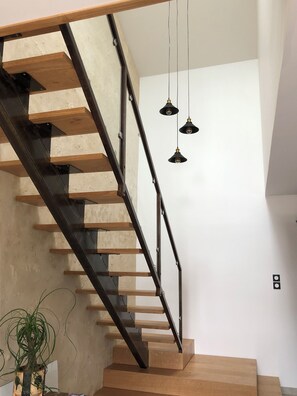 Eine Treppe mit Holzbodenstufen und Metallgeländern, eine hängende Leuchte und ein Blumentopf.