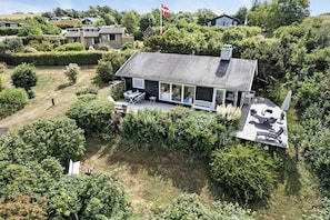 A house with a large deck, outdoor seating, and a flag. - Sunset over Sejerø Bay from house (Fårevejle)