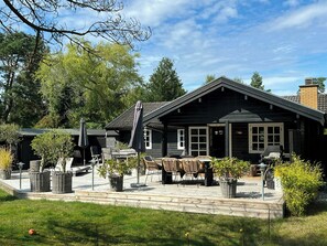 A two-story house with a patio area, outdoor furniture, and a barbecue grill. - Authentic log cabin on large enclosed natural plot (Vig)