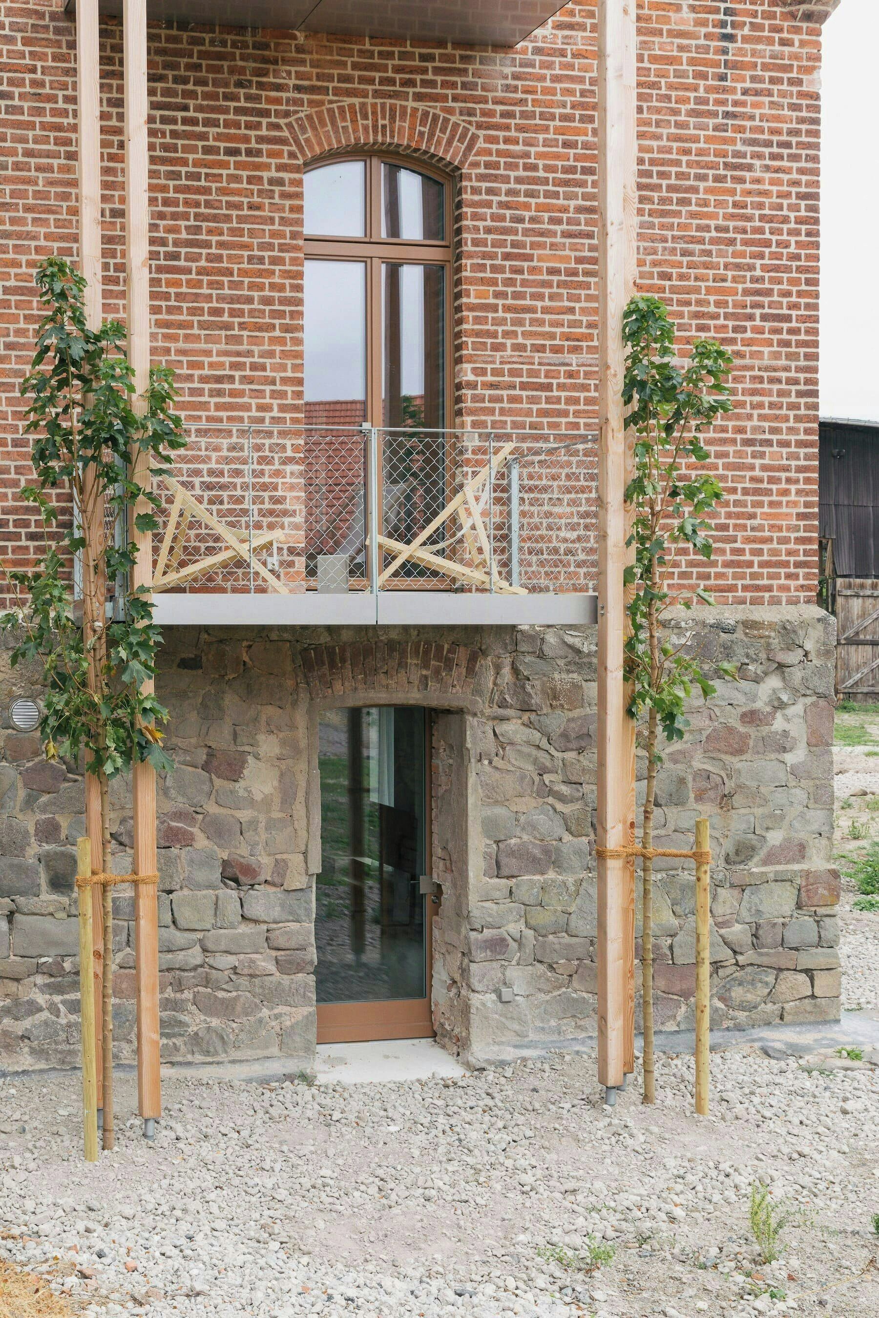 En byggnad med en fasad av sten, en träbalkong och ett metallräcke.