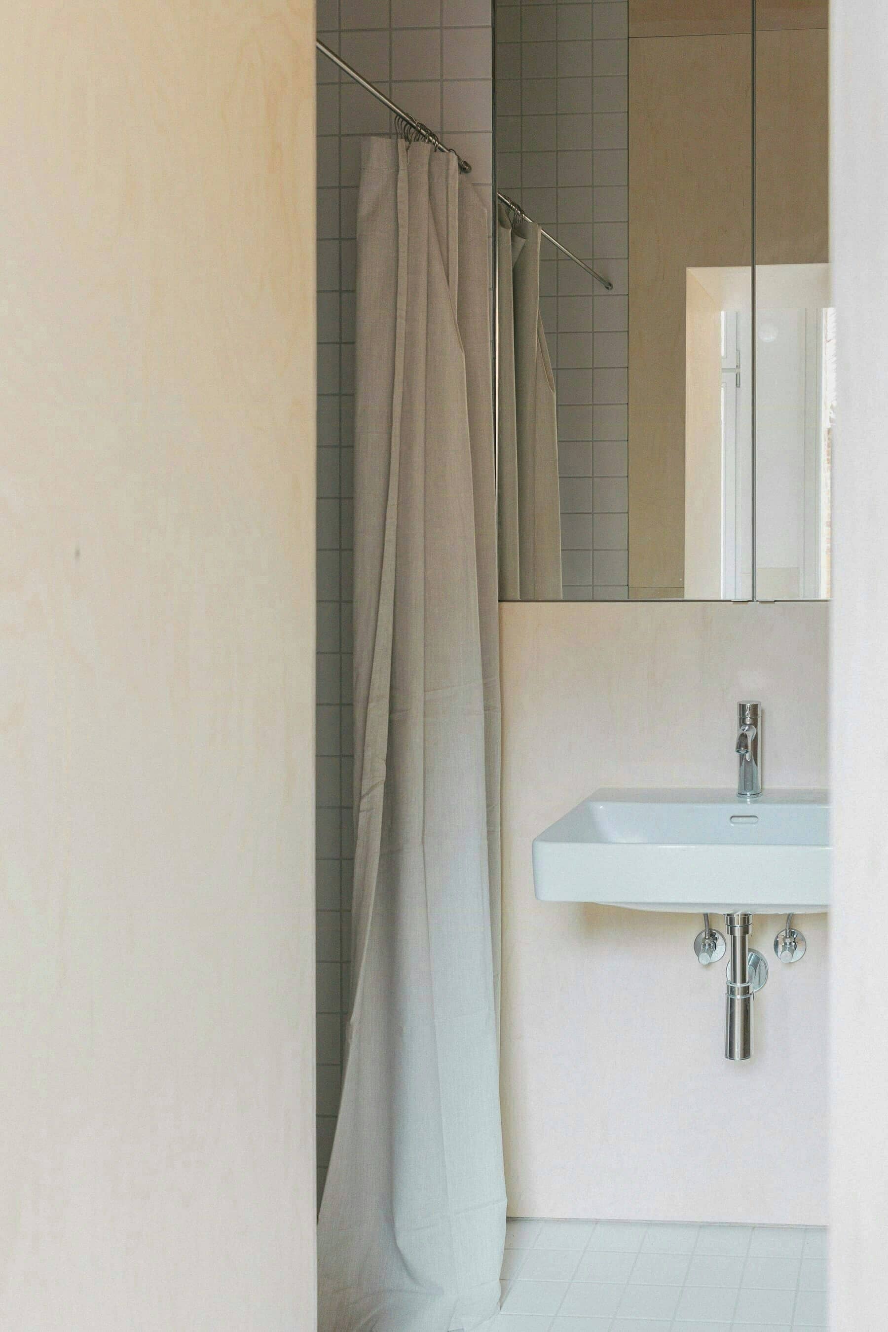 A bathroom with a shower curtain, a sink, and a mirror.